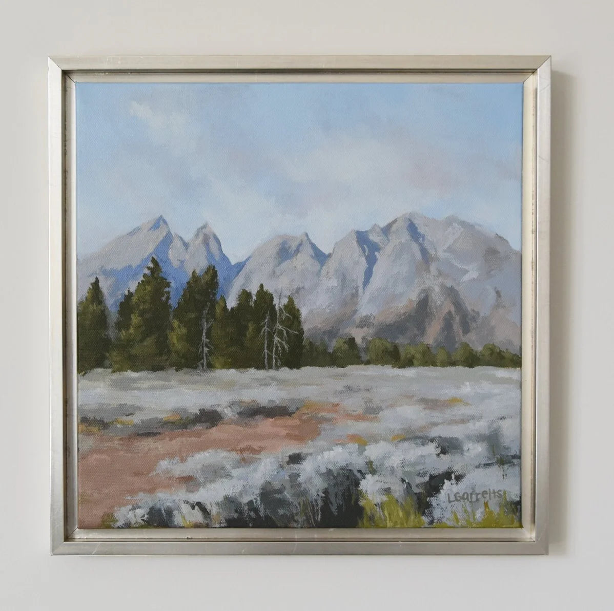 Framed painting of a mountain landscape with trees and snow.